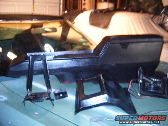 Car's center console and some brackets laid out on a light green surface