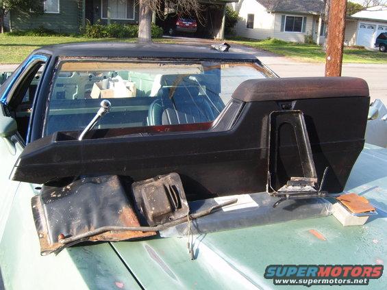 Green Ford Ranchero hood with disassembled interior parts and a black center console