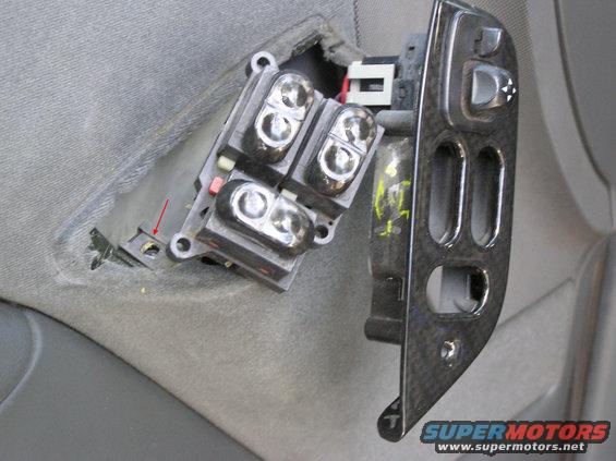 Car door window and lock switch panel removed from gray upholstery, showing four window switches and a control panel with lock and mirror buttons
