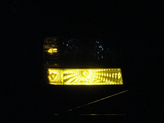 Headlight with yellow tint and internal reflector pattern, dark background