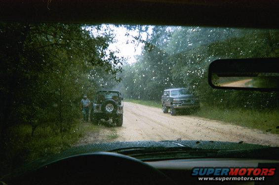 Dark gray SUV on a dirt road, seen from inside another vehicle