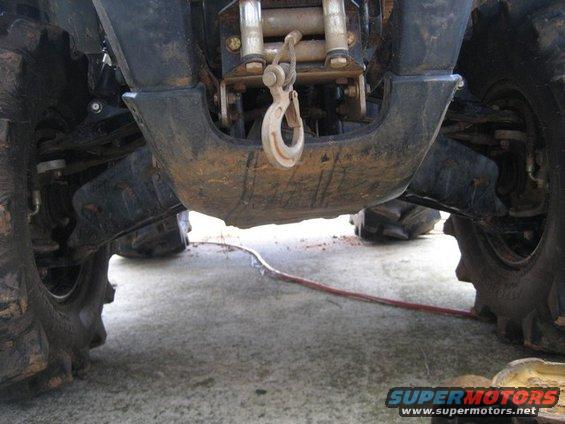 All-terrain vehicle undercarriage with winch and hook, showing large tires and suspension components