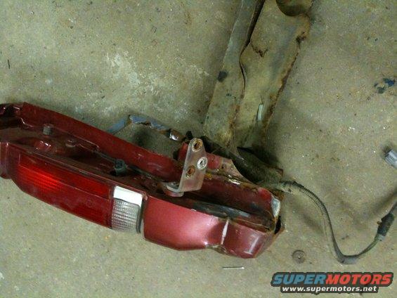 Red taillight assembly and rusted metal bracket on concrete floor