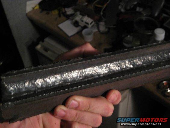 Close-up of a metal part with visible weld seams, held by a hand