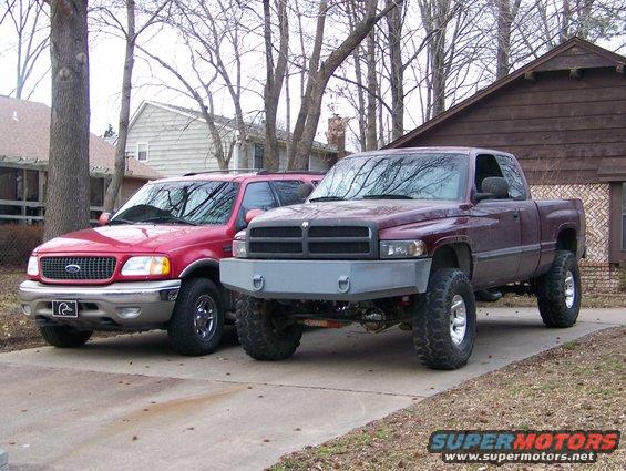Maroon Dodge Ram pickup with aftermarket bumper and red Ford Expedition parked side-by-side