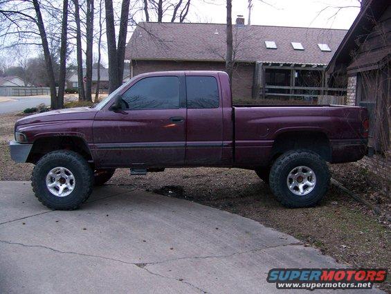 Maroon 2001 Dodge 1500 pickup truck with a lift kit and aftermarket wheels, parked on a driveway