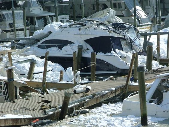 Damaged yacht covered in snow at a marina dock