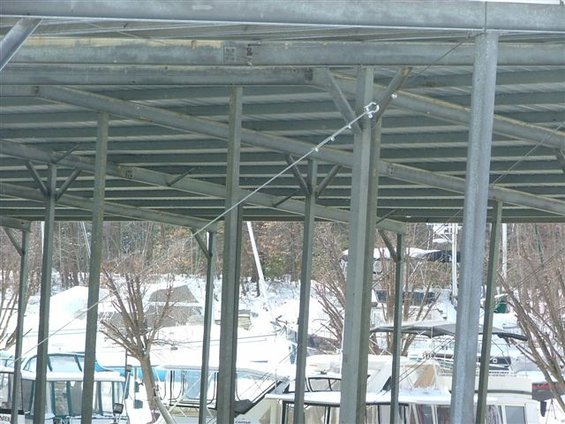 Boats docked under a metal canopy with snow on the ground