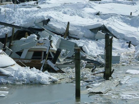 Boats and docks destroyed by snow and ice, with debris scattered in the water