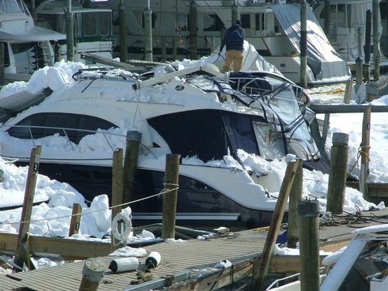 Boat covered in snow at a marina with a person on top