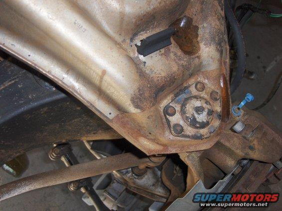 Close-up of rusty vehicle suspension part with some hoses and linkages visible