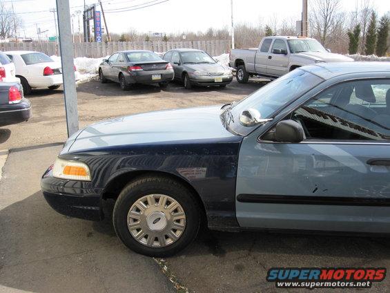 2003 Ford Crown Victoria front fender and door, parked next to other cars and a pickup truck