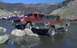 1976 Ford F-250 - Two lifted trucks are parked in a rocky, shallow body of water with a mountainous backdrop.