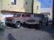 1976 Ford F-250 - Two lifted Ford trucks, a red Bronco and a brown F-250, are parked in an alleyway.