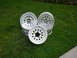 1988 Ford Bronco - Three aluminum alloy wheels are displayed on a grassy lawn.