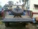 1976 Ford F-250 - Rear view of a brown pickup truck with a spare tire in the bed, parked next to a trailer.