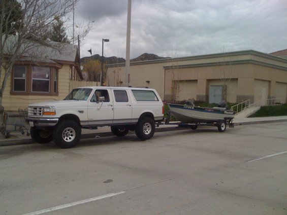 White SUV towing a boat with 'Tracker' visible on the side