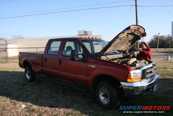 Red Ford F-350 pickup truck with hood open, driver's side visible, parked on grass