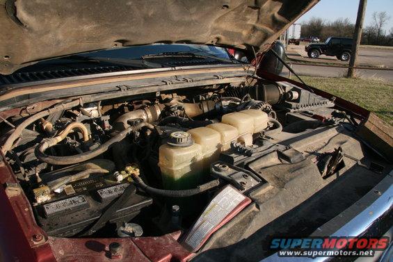 Engine bay with hood open. Black SUV visible in background
