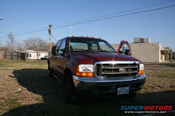 Red Ford F-250 Super Duty truck with driver's door open. License plate R1X-265
