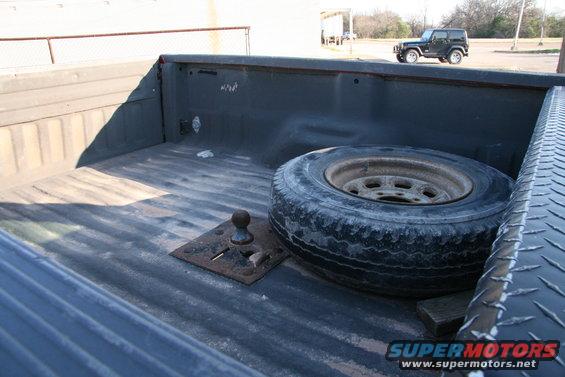 pickup truck bed with spare tire and fifth wheel hitch, another SUV in background