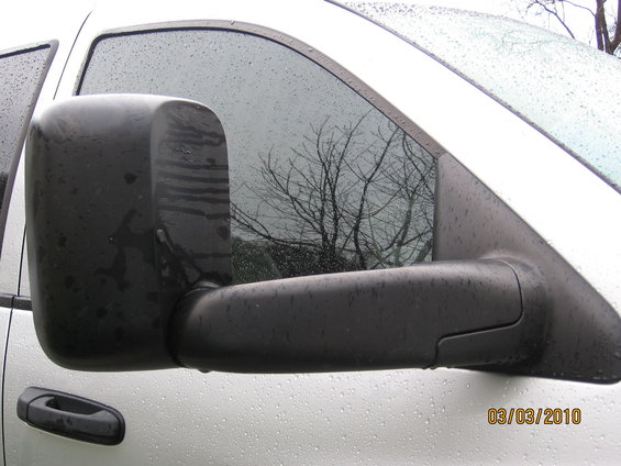 Black tow mirror on a white truck with water droplets
