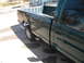 1995 GMC Sierra 1500 - A green 1995 GMC Sierra 1500 pickup truck is parked on a driveway, showing damage to its rear fender.