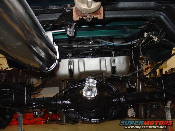 Underside view of a truck's rear axle, driveshaft, and exhaust system. The vehicle appears to be on a lift