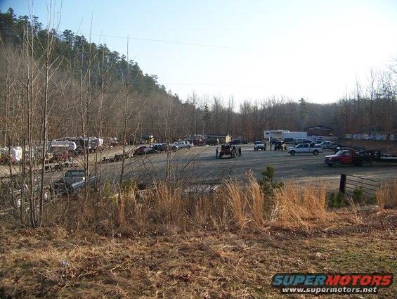 Parking lot full of trucks, trailers, and RVs near a wooded area
