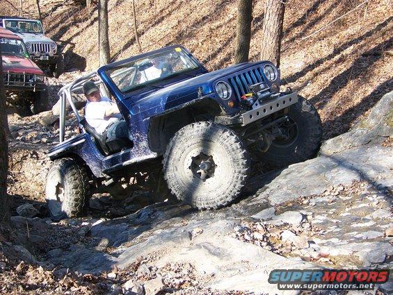 Blue Jeep Wrangler navigating rocky terrain