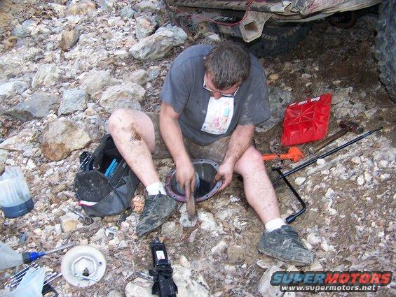 Man working on differential with tools and red gas can scattered around