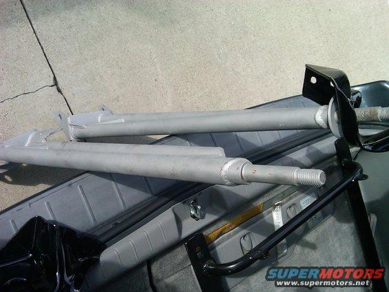 Two gray radius arms with threaded ends and black mounting brackets