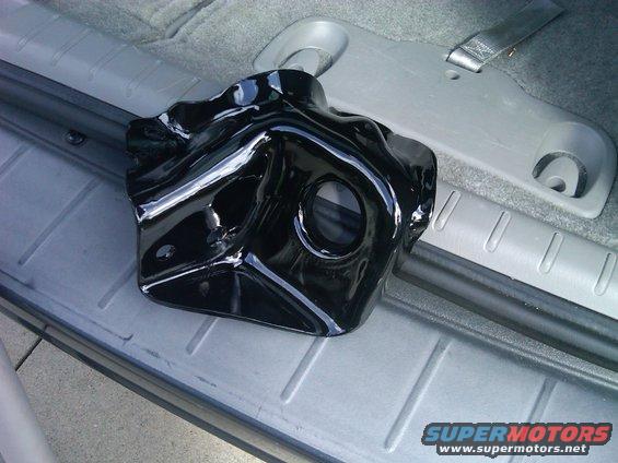 Black metal suspension component resting on a gray interior surface