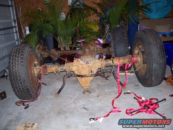 Rear axle assembly with two tires attached, resting on the floor indoors