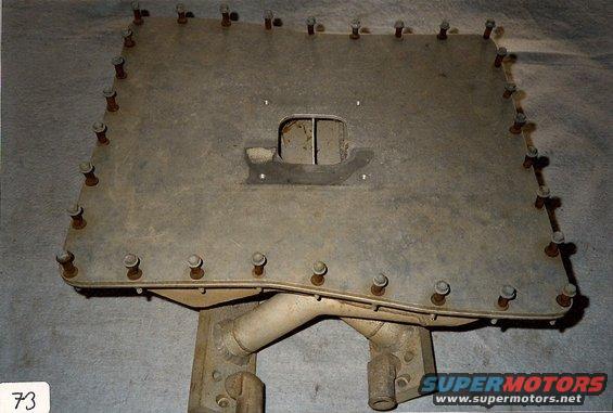 Metal plate with numerous bolts around the perimeter and a central cutout, attached to a metal bracket
