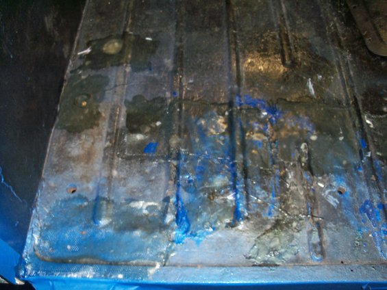 Interior floor of a vehicle with blue paint and rust