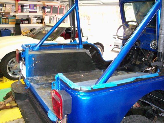 Blue Jeep CJ5 in garage, roll cage installed, rear view