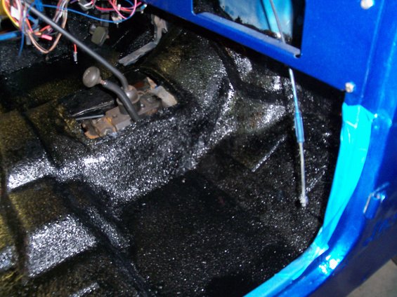 Interior of blue Jeep showing black textured floor and manual shifter