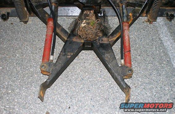 Black snow plow attachment with red hydraulic cylinders and a bird's nest in the center