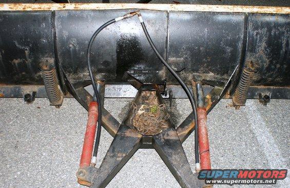 Snow plow attachment with red hydraulic cylinders and black hoses