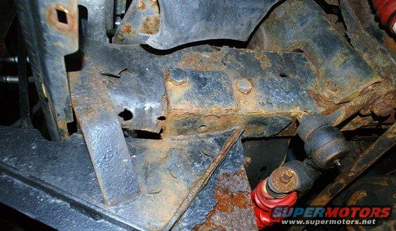 Rusted frame and suspension parts, red shock absorber visible