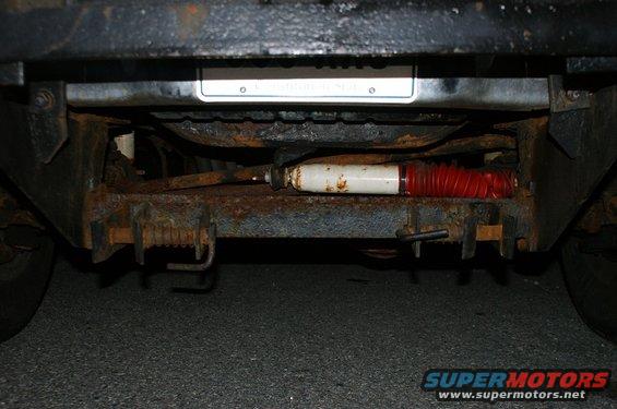 Undercarriage view showing rusty frame, suspension components, and a license plate