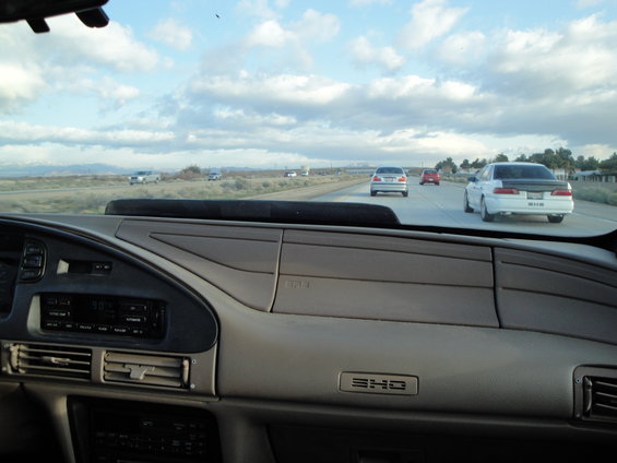 View from inside a car looking at the dashboard and the highway ahead with other cars driving