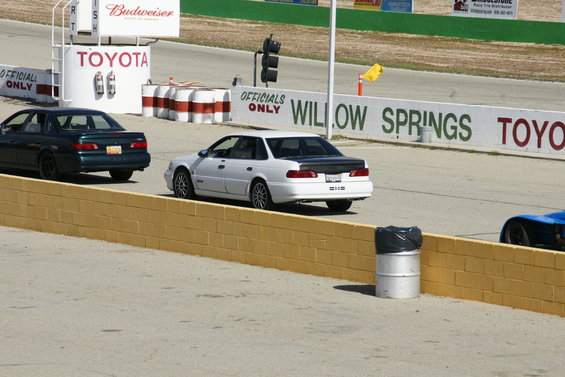 White 1995 Ford Taurus sedan with a black spoiler and tinted rear window on a race track