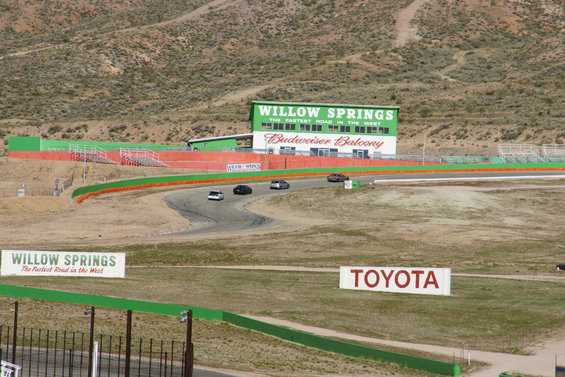 Cars on a race track with Willow Springs building in background