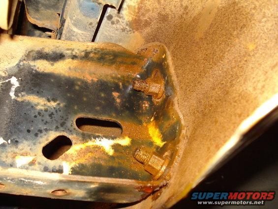 rusted metal bracket with two bolts visible, showing signs of corrosion