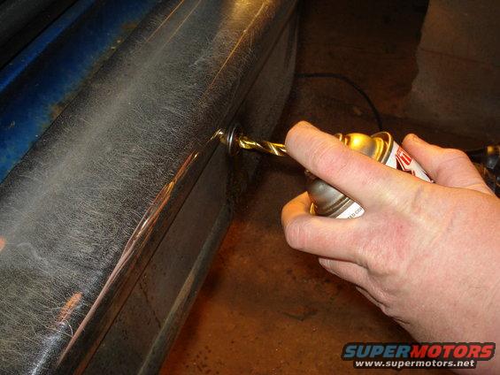 Drilling into a chrome bumper with a spray can nearby