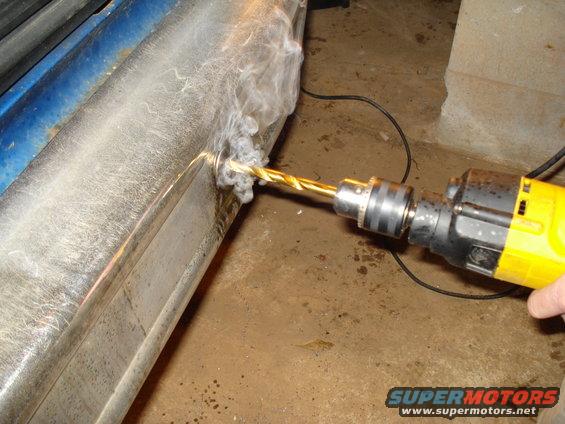 Drill bit smoking as it bores into a chrome bumper