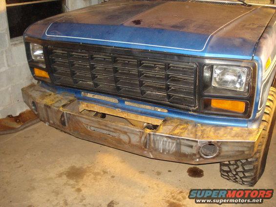 Blue pickup truck front end with a custom metal bumper and a black grille. The truck appears to be from the early 1980s