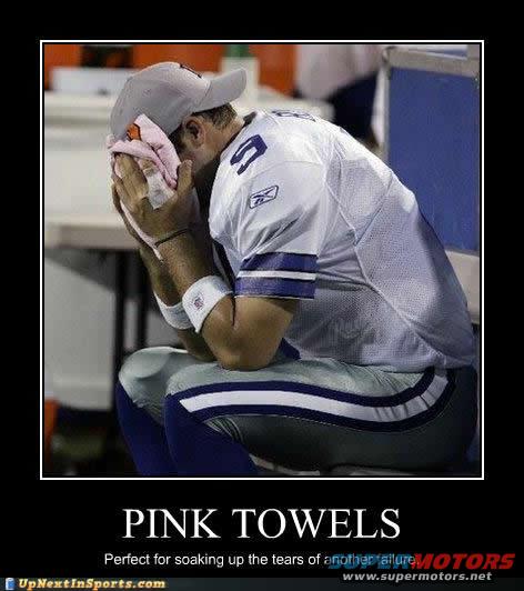 Football player in white jersey and grey cap, wiping face with pink towel
